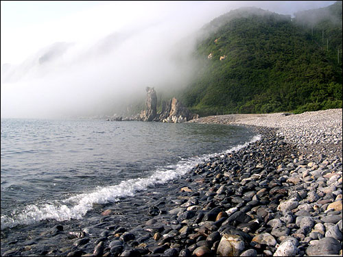 능동몽돌해변 섬 기슭에 해무가 끼어 한폭의 수묵화를 그려냈다. 해무는 다시 산등성이을 채색해갔다. 